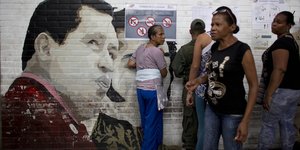 Ein Graffiti von Maduro, daneben stehen mehrere Menschen