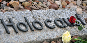 Eine Marmorplatte mit der Aufschrift "Holocaust", darauf liegen Rosen
