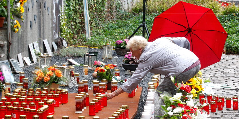 eine Frau stellt eine Friedhofskerze zu vielen anderen