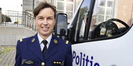 Eine Frau in Uniform neben der Fahrertür eines Polizeiautos