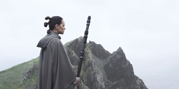 Eine Frau steht auf einem Hügel mit einem Stab in der Hand