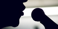 Ein Mensch spricht in ein Mikrofon