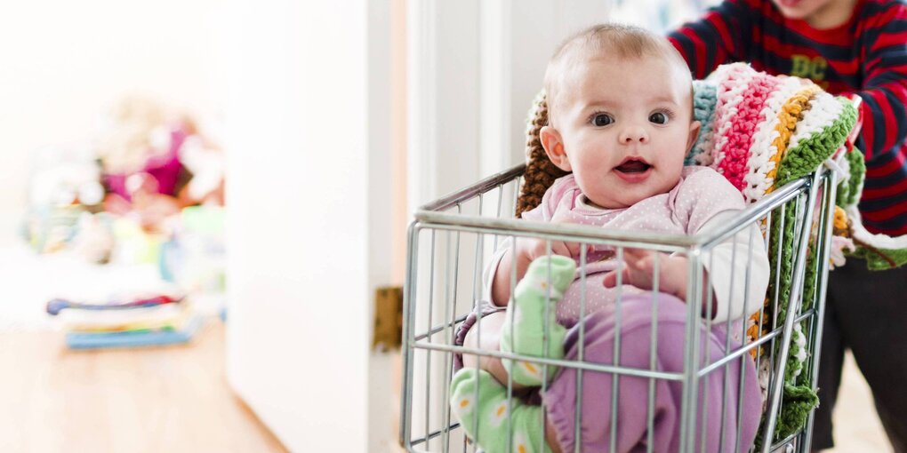 Kleines Kind schiebt Baby in einem Wagen