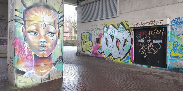 Ein Graffito zeigt eine Frau an einem Betonpfeiler Ein Graffito zeigt eine Frau an einem Betonpfeiler