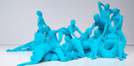 Mehrere ineinander verschlungene Tänzer*innen in blauen Ganzkörperanzügen
