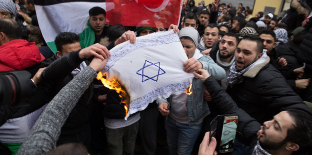 Demonstranten verbrennen eine Fahne mit Davidstern
