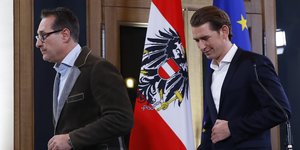 Zwei Männer laufen vor einer österreichischen Flagge