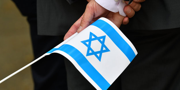 Eine Hand hält ein Israel-Fähnchen