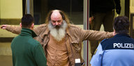 Ein Mann mit langem Bart wird von Sicherheitspersonal untersucht