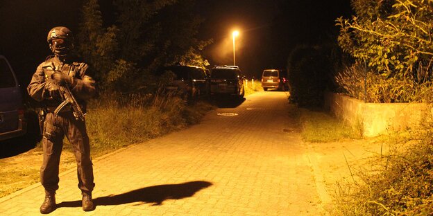 Ein Polizist im Dunkeln auf einer gepflasterten Weg, der von einer Laterne beleuchtet wird