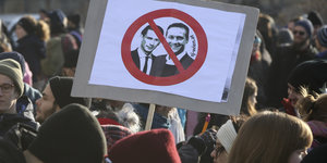 Ein Demonstrierender hält beim Protest gegen die neue österreichische Regierung ein Schild hoch, auf dem Bundeskanzler Kurz und Vizekanzler Strache durchgestrichen sind.