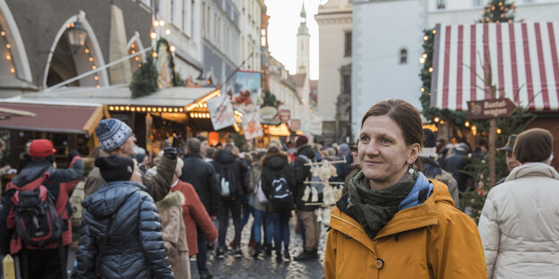 Eine Frau, Eva Wittig, im Hintergrund Besucher eines Weihnachtsmarktes