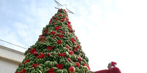 Ein Mann schmückt einen Weihnachtsbaum aus Bananen