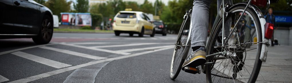 Ein Mensch fährt neben Autos auf dem Fahrrad