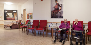 Drei alte Menschen sitzend in einem Zimmer - ein paar Sessel sind leer.