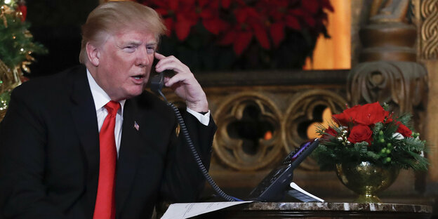 Donald Trump hält sich mit interessierter Miene einen Telefonhörer ans Ohr