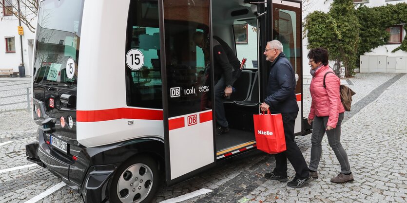 Menschen steigen in einen kleinen Bus