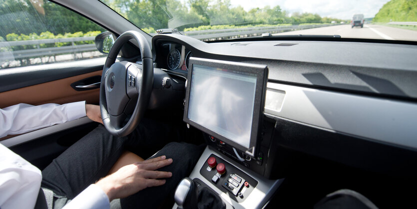 Die Hände eines Autofahrers liegen in seinem Schoß statt auf dem Lenkrad