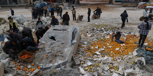 Ein Marktplatz nach einem Luftangriff, Menschen stehen um ein zerstörtes Auto