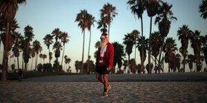Ein Mann mit Bart und Weihnachtsmannmütze unter Palmen am Strand