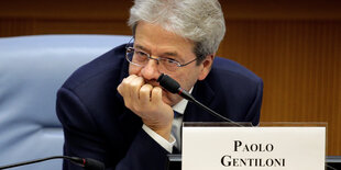 Paolo Gentiloni sitzt nach vorn gebeugt an einem Tisch