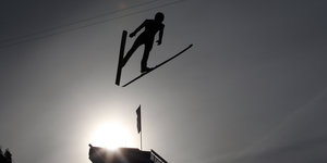Ein Skispringer fliegt über den Himmel