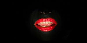 ein rotgeschminkter und beleuchteter Mund vor schwarzem Hintergrund