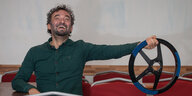 Fahrlehrer Süleyman Tuncel hält lachend ein Lenkrad