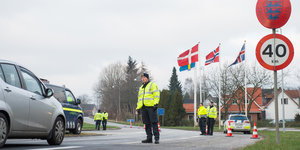 Ein Mann in einer Neonweste steht vor einem Auto, hintern ihm wehen dänische Flaggen