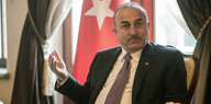 Ein Mann in Anzug, hinter ihm eine türkische Flagge