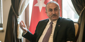 Ein Mann in Anzug, hinter ihm eine türkische Flagge
