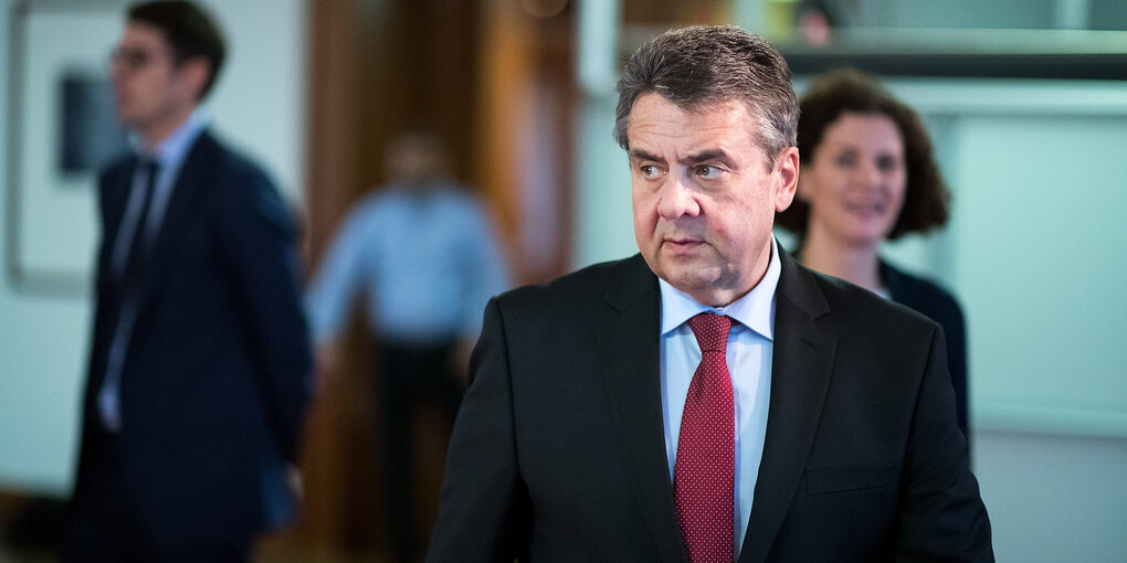 Sigmar Gabriel geht, hinter ihm steht mehrere Menschen