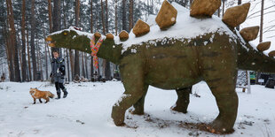 Eine Frau mit Fuchs an der Leine, ein Dino aus Stein