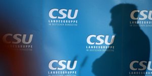 Der Schatten eines Mannes vor CSU-Schriftzügen