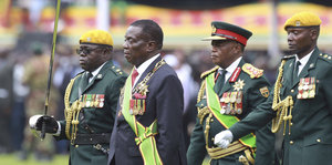 Vier Soldaten, drei davon in Paradeuniform, einer in Zivil, aber mit seinen Orden