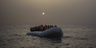 Ein Schiff mit Flüchtenden vor einer blassen Abendsonne