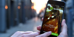 Jemand hält ein Smartphone in der Hand und tippt auf die Spotify-App