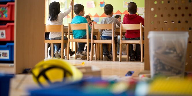 Kinder sitzen in einer Kita an einem Tisch