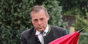 NPD-Politiker Udo Pastörs faltet einen Regenschirm zusammen.