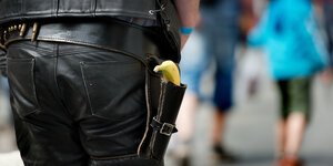 Eine Person in Cowboy-artigem Lederdress hat eine Banane in der Pistolenhalterung hängen.