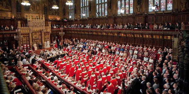 Blick ins vollbesetzte House of Lords. An dessen Frontseite sitzt die Queen