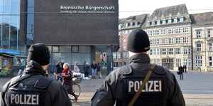 Zwei Männer in Polizeiuniform stehen vor der Bremischen Bürgerschaft.