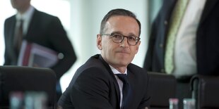 Heiko Maas sitzt mit verkniffenen Lippen an einem Tisch