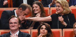 Der Schauspieler Vincent Lindon gibt Catherine Deneuve einen Handkuss. Beide sitzen im Rang eines Theaters