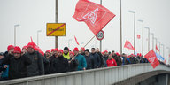 Menschen auf einer Brücke, eine große rote IG-Metall-Fahne weht darüber
