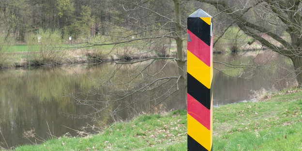 Am Ufer der Neiße steht ein Pfahl in den Symbolfarben Deutschlands