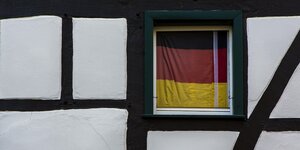 Eine Deutschlandfahne behängt ein Fenster in einem Fachwerkhaus