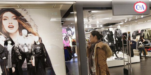 Frau geht an einer C&A Filiale in einem chinesischen Einkaufszentrum vorbein