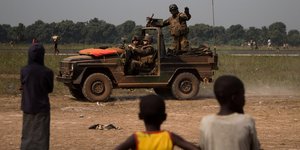 Ein französischer Soldat auf einem Jeep winkt Kindern zu