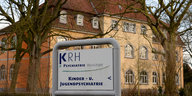 Ein Schild mit dem Schriftzug "Psychiatrie Wunstorf" steht vor einem großen alten Gebäude.